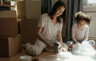 Mother and daughter sitting on the floor with wrapping bowls for the move