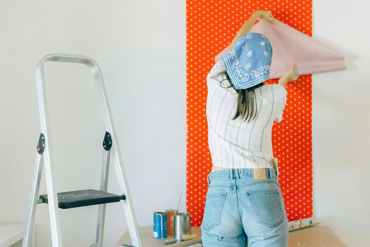 A young woman is hanging red polka-dotted wall papers